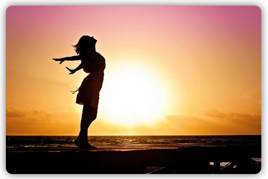 A woman giving a relaxed pose in front of the sun near a beach