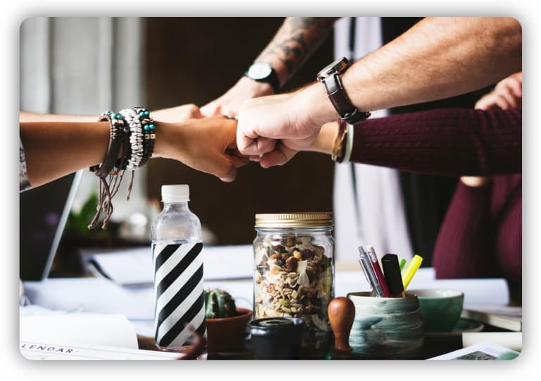 A group of five people fist bumping each other