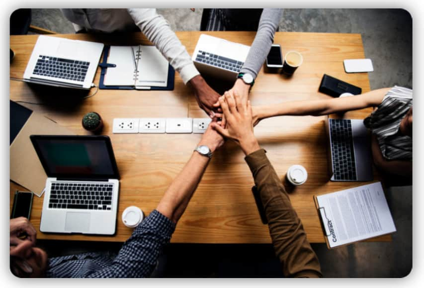 A group of five people putting their hands together