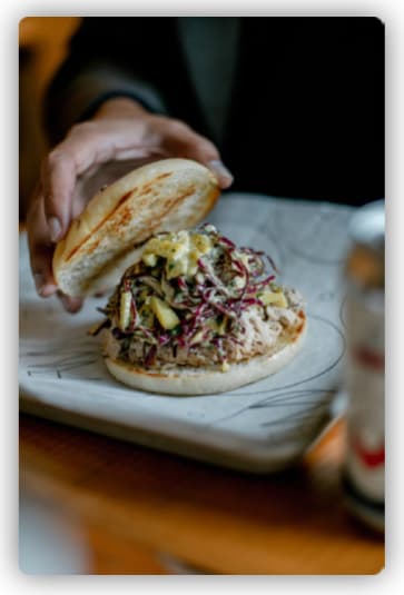 A chef showing the insides of a burger while placing its top bun